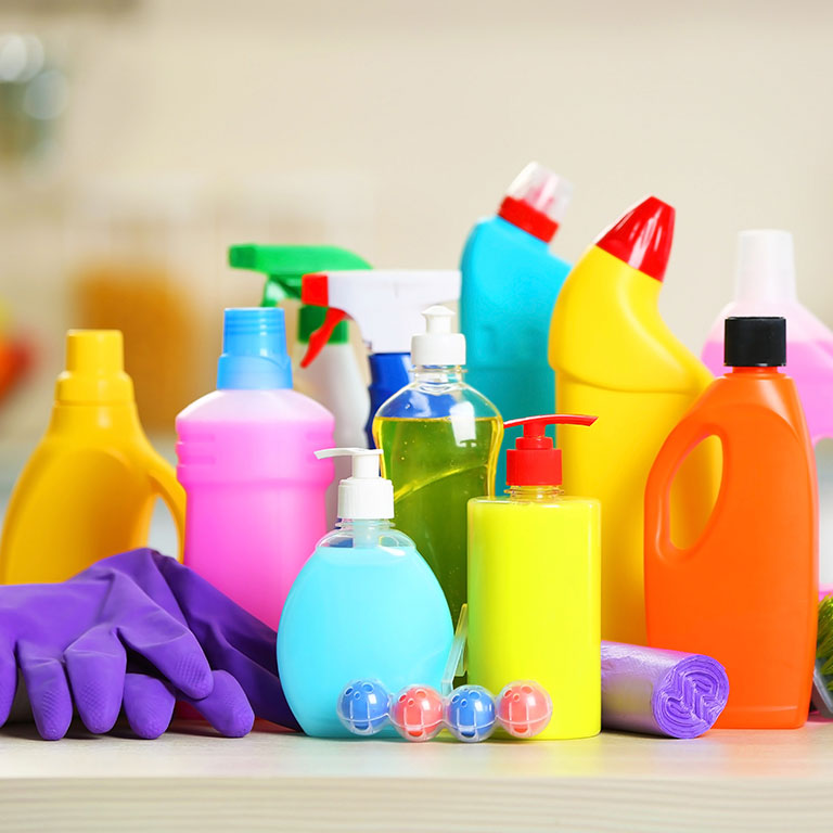 Different cleaning solutions and chemicals in a group on the counter along with some rubber gloves