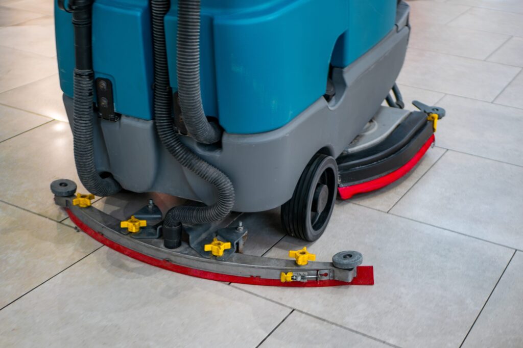 Custodian using a floor scrubber to clean a tile floor