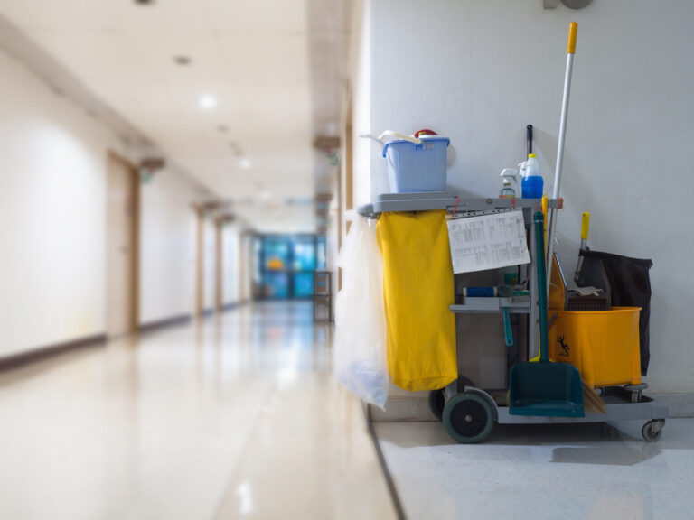 Custodian cart with cleaning supplies on it in an empty hallway