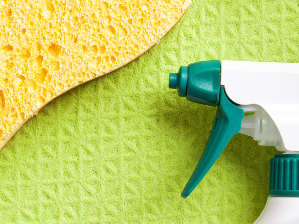 Closeup image of a sponge, cleaning cloth, and a cleaning solution spray bottle